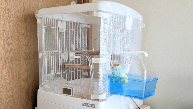 気泡緩衝材を切ってバードバスを取り付けたセキセイインコのケージ